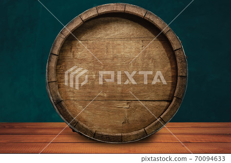 Beautiful wooden barrel on a red wood table and green  wall background.. 70094633