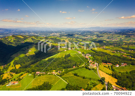 Aerial view of green hills and vineyards with mountains in background. Aerial view of green hills and vineyards with mountains in background. 70094922