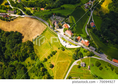 Aerial view of green hills and vineyards with mountains in background. Aerial view of green hills and vineyards with mountains in background. 70094927