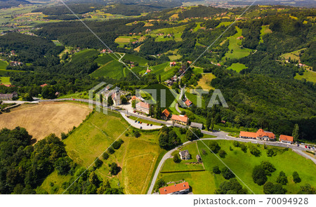 Aerial view of green hills and vineyards with mountains in background. 70094928