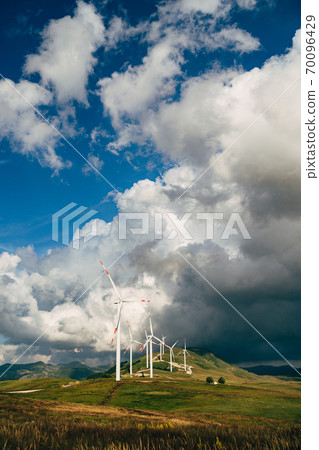 A series of wind generators amid epic clouds. 70096429