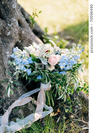 bridal bouquet of pink roses, blue campanula, olive branches, artemisia, eryngium ,white ribbons near the tree on the ground 70096490