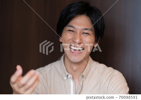 一個笑著打電話的年輕人的臉部特寫 70098591