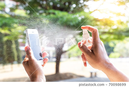 Men use alcohol spray to get rid of bacteria and viruses on mobile phones, Inhibition and prevention of Covid-19 virus, protect virus concept. 70098699