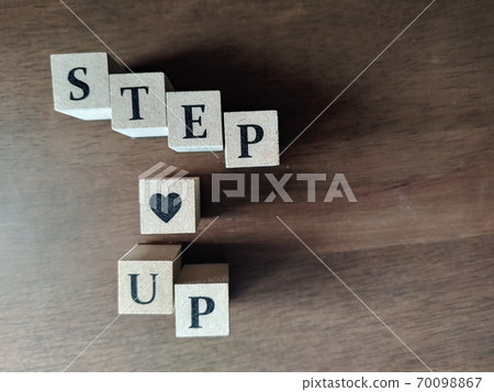 Dice letters 2 lined up with STEP UP in bright light 70098867