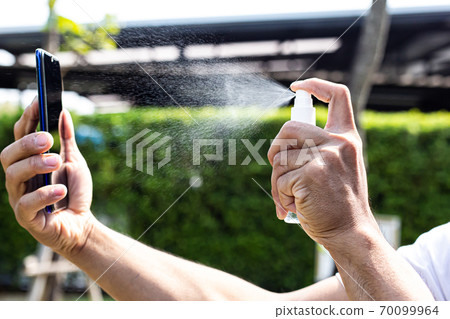 Man uses a spray of alcohol to get rid of bacteria and viruses, Inhibition and prevention of Covid-19 virus infection using 70 percent alcohol, protect virus concept. 70099964