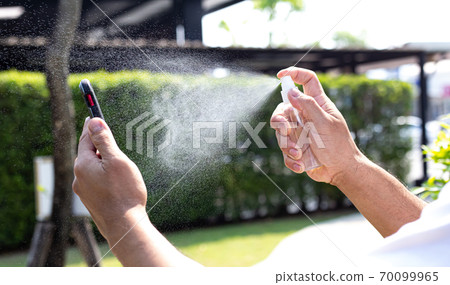 Man uses a spray of alcohol to get rid of bacteria and viruses, Inhibition and prevention of Covid-19 virus infection using 70 percent alcohol, protect virus concept. 70099965