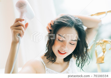 the woman is drying her hair the woman is drying her hair 70100334