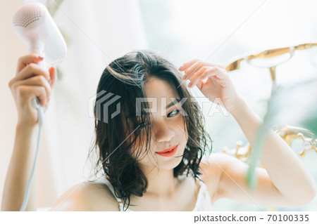 the woman is drying her hair the woman is drying her hair 70100335