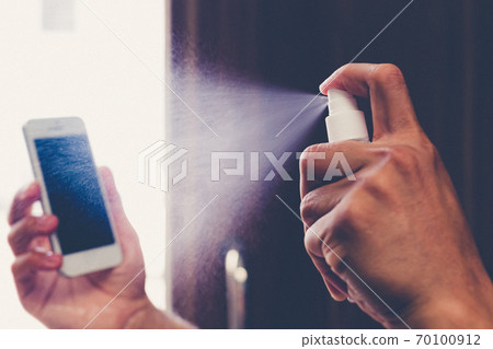 Men use alcohol spray to get rid of bacteria and viruses on mobile phones, Inhibition and prevention of Covid-19 virus, protect virus concept. 70100912