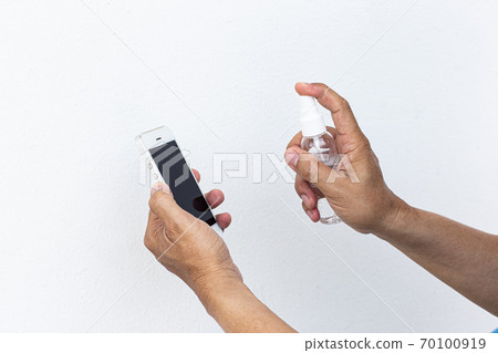 Men use alcohol spray to get rid of bacteria and viruses on mobile phones, Inhibition and prevention of Covid-19 virus, protect virus concept. 70100919