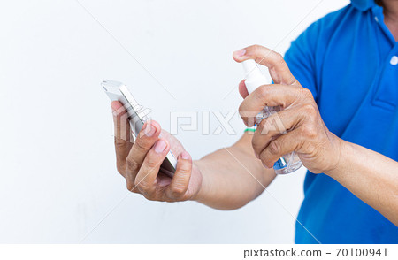 Men use alcohol spray to get rid of bacteria and viruses on mobile phones, Inhibition and prevention of Covid-19 virus, protect virus concept. 70100941