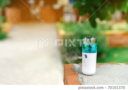 Alcohol nano mist sprayer for hand cleaning to prevent the spread of the Corona virus (Covid-19) on a walkway to a coffee shop. Modern health technology. New normal lifestyle. Selective focus Alcohol nano mist sprayer for hand cleaning to prevent the spread of the Corona virus (Covid-19) on a walkway to a coffee shop. Modern health technology. New normal lifestyle. Selective focus 70101370