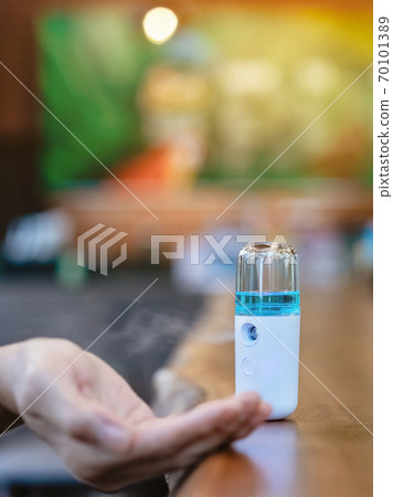Alcohol nano mist sprayer for hand cleaning to prevent the spread of the Corona virus (Covid-19) to serve customers at coffee shop. Modern health technology. New normal lifestyle. Selective focus 70101389