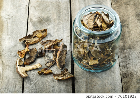 Dried mushrooms in a glass jar on a wooden table. 70101922