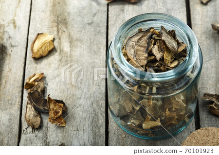 Dried mushrooms in a glass jar on a wooden table. 70101923