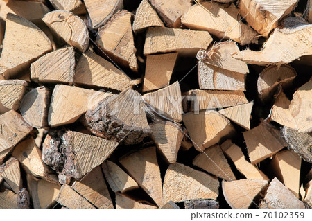Chopped firewood stacked in a woodpile, view from the end of the masonry Chopped firewood stacked in a woodpile, view from the end of the masonry 70102359