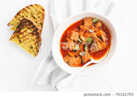 Slow cooked pork with vegetables, carrots, onions and ripe tomatoes with sweet peas and bay leaves in a plate. View from above. Comfortable homemade food 70102705
