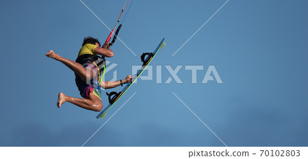 Athletic man jump on kite surf board on a sea waves, kiteboarding action photos 70102803