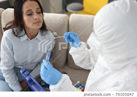 Doctor in antiplague protective suit takes swab with cotton swab to patient at home Doctor in antiplague protective suit takes swab with cotton swab to patient at home 70103847