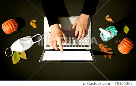Person using a laptop computer with a mask and a sanitizer bottle Person using a laptop computer with a mask and a sanitizer bottle 70104305