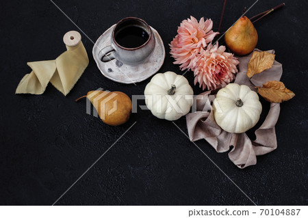 Autumn still life composition. Cup of coffee, pear fruit and white pumpkins with pink dahlia flowers on black table background. Moody fall, Thanksgiving design. Flat lay, top view. Autumn still life composition. Cup of coffee, pear fruit and white pumpkins with pink dahlia flowers on black table background. Moody fall, Thanksgiving design. Flat lay, top view. 70104887