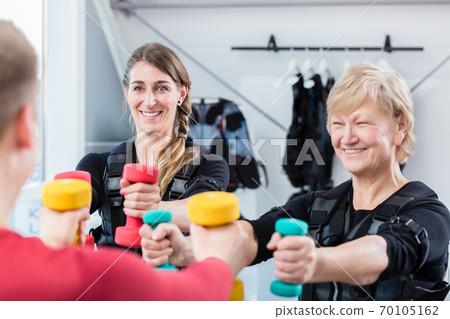 Senior and young woman with dumbbells in wireless ems gym 70105162