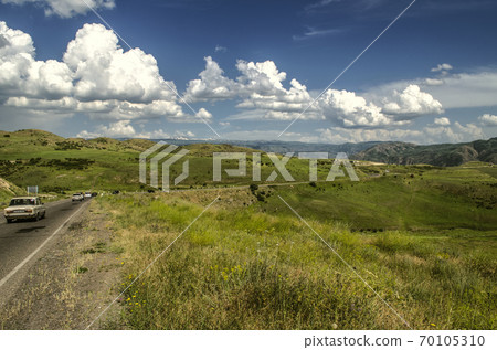 Turn on the road, located high in the mountains of the Gegham range against the blue sky covered with Cumulus clouds in Armenia. 70105310