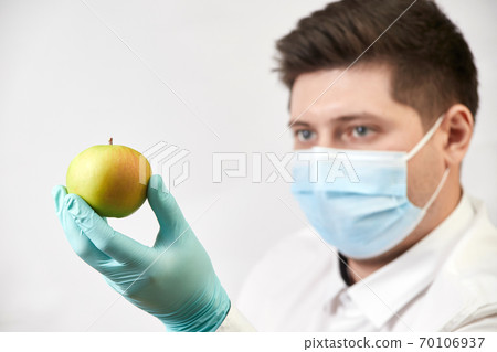 coronavirus concept, salesman with apple in gloves and mask on white background coronavirus concept, salesman with apple in gloves and mask on white background 70106937