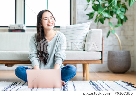 Young woman using a computer in the living room Young woman using a computer in the living room 70107390