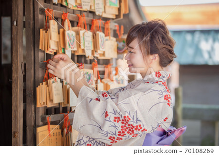 A woman in a yukata tying a votive tablet A woman in a yukata tying a votive tablet 70108269