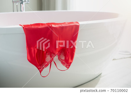 Nightgown in red hung on the bathtub 70110002