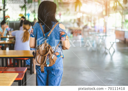 Mini portable alcohol gel bottle to kill Corona Virus(Covid-19) hang on a leather shoulder bag of a woman wear a protective mask at a cafeteria. New normal lifestyle. Selective focus on alcohol gel Mini portable alcohol gel bottle to kill Corona Virus(Covid-19) hang on a leather shoulder bag of a woman wear a protective mask at a cafeteria. New normal lifestyle. Selective focus on alcohol gel 70111418