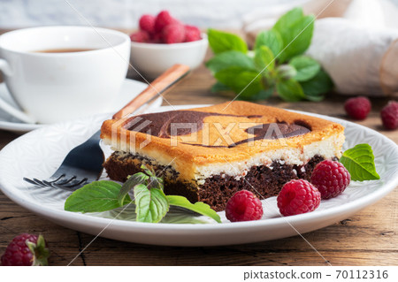 A piece of double-layer cake on a plate of chocolate brownies and curd cheesecake with raspberries. copy space 70112316