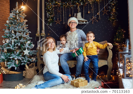 Happy family in the room with the Christmas tree. 70113163