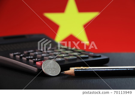 Two hundred Vietnam Dong coin on reverse (VND) with black calculator and two pencils 70113949
