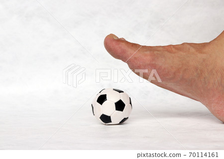 Mini ball of football on the floor under the foot with white background. Concept of sport. 70114161