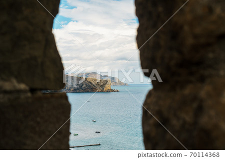 View of the sea coast through the window in the fortress. View of the sea coast through the window in the fortress. 70114368