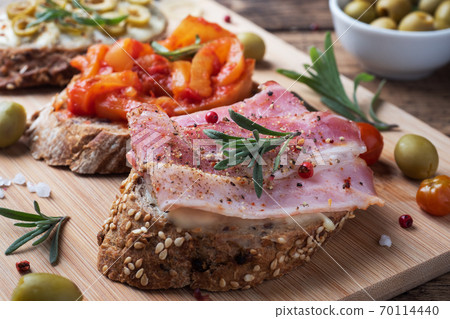 Wholegrain bread sandwiches with cream cheese, bacon and olives canned peppers with tomato on wooden background. Wholegrain bread sandwiches with cream cheese, bacon and olives canned peppers with tomato on wooden background. 70114440