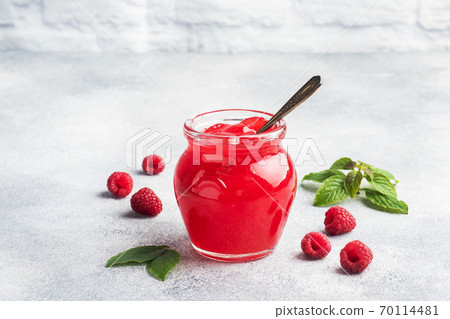 Homemade raspberry jam in a glass jar and fresh raspberries with mint on a grey concrete background. Copy space Homemade raspberry jam in a glass jar and fresh raspberries with mint on a grey concrete background. Copy space 70114481