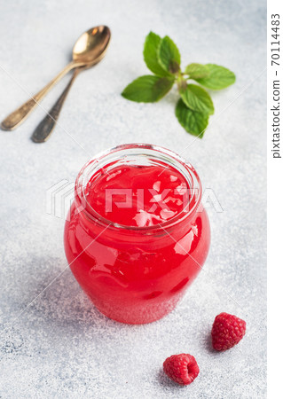 Homemade raspberry jam in a glass jar and fresh raspberries with mint on a grey concrete background. Copy space Homemade raspberry jam in a glass jar and fresh raspberries with mint on a grey concrete background. Copy space 70114483