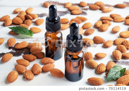 Almond essential oil in dark glass bubbles and fresh almond nuts. Aromatherapy oil natural organic cosmetic. Almond essential oil in dark glass bubbles and fresh almond nuts. Aromatherapy oil natural organic cosmetic. 70114519