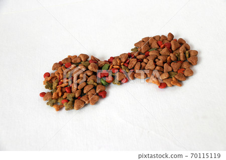 Heap of cat food set to dumbbell shape on the white floor. The concept of cat strength or healthy. Heap of cat food set to dumbbell shape on the white floor. The concept of cat strength or healthy. 70115119