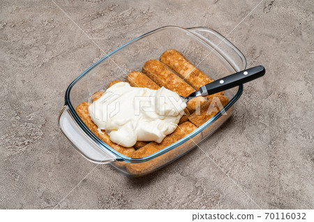 tiramisu dessert cooking - Traditional Italian Savoiardi ladyfingers Biscuits and cream in glass baking dish on concrete background tiramisu dessert cooking - Traditional Italian Savoiardi ladyfingers Biscuits and cream in glass baking dish on concrete background 70116032