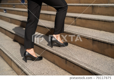 business woman with high heel shoes walking up on the stairs in city 70117875