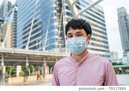 asian man wearing medical mask for protection from coronavirus (covid-19) pandemic in city 70117889