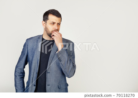 Male businessman with a beard, looks tense and nervous with his hands on his mouth biting his nails Male businessman with a beard, looks tense and nervous with his hands on his mouth biting his nails 70118270