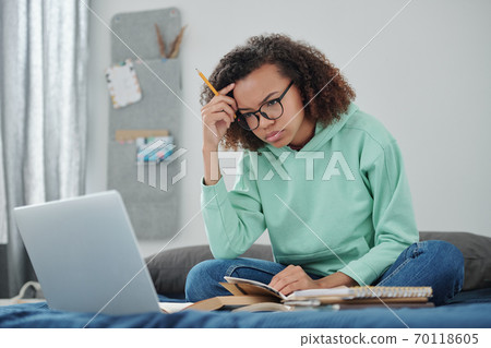 Young student in jeans and hoodie trying to concentrate in front of laptop Young student in jeans and hoodie trying to concentrate in front of laptop 70118605