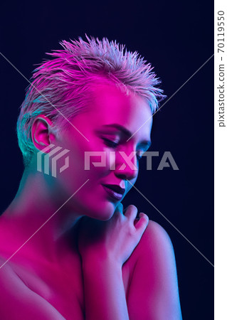Portrait of female fashion model in neon light on dark studio background. 70119550