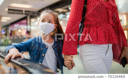 Mother and daughter with face mask indoors in shopping center, coronavirus concept. Mother and daughter with face mask indoors in shopping center, coronavirus concept. 70120469